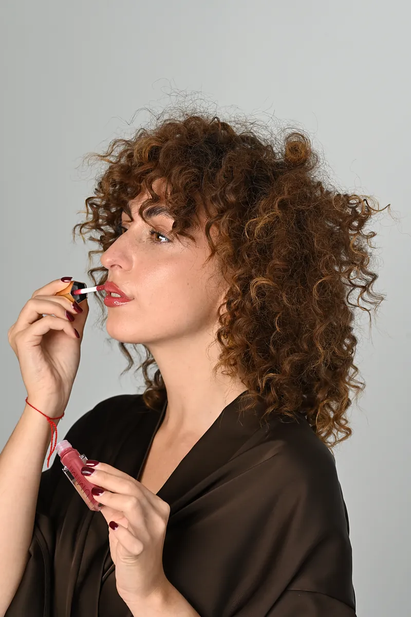 A woman applying LUMIMI lip gloss